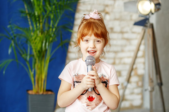 The little ore girl sings to the microphone. The concept is childhood, lifestyle, music, singing, listening, hobbies.