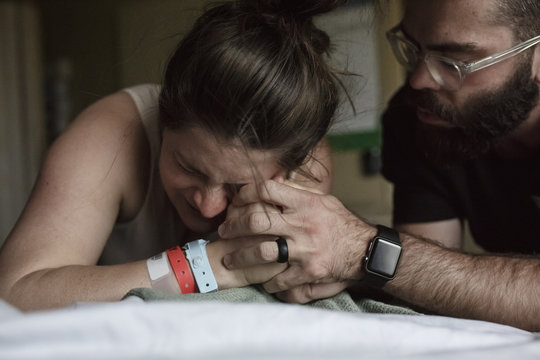 Close up of man comforting painful pregnant woman on hospital bed