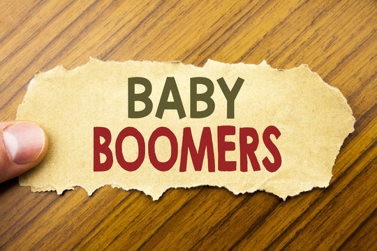Writing text showing Baby Boomers. Business concept for Demographic Generation written on note paper on the wooden background with human finger. Vintage style.