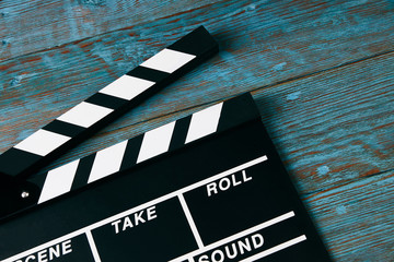 Movie clapper board. Black clapperboard on blue wooden background with copy space, close-up. Cinema...