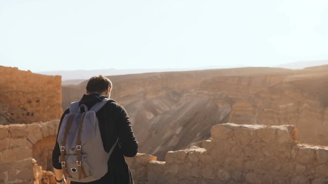 Male tourist photographs amazing mountain scenery. Young man with backpack takes photos. Freedom. Masada Israel 4K.