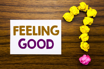 Fototapeta premium Handwritten text showing Feeling Good. Business concept for Happy Positive Attitude Written on sticky note paper, wooden background with question mark from sticky note. For asking questions.