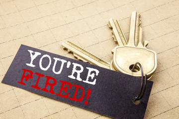 Conceptual hand writing text caption showing You Are Fired. Business concept for Unemployed or Discharge written on note paper attached to the keys note paper on the texture background.