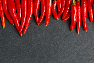 Fresh ripe red hot chili peppers on a black background