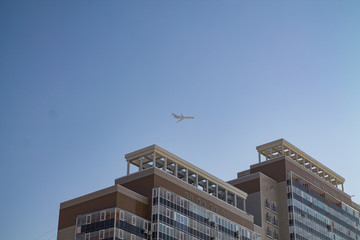a plane flying over a tall modern building with lots of windows