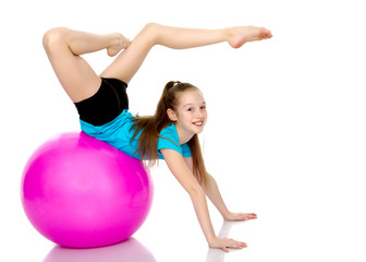 Fototapeta na wymiar little girl doing exercises on a big ball for fitness.