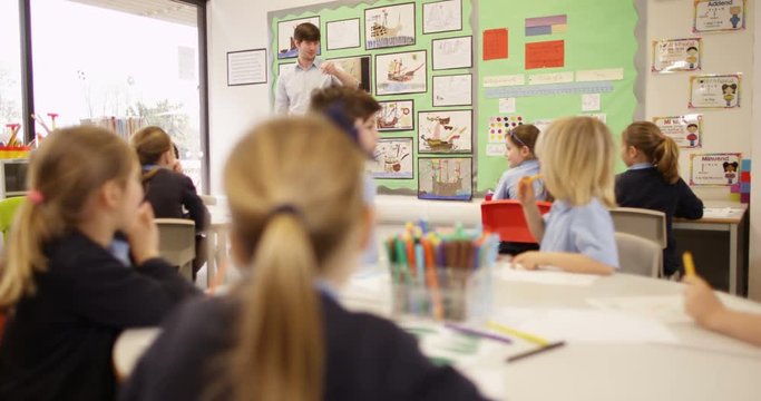 4K Primary school teacher talking to class of young children & asking questions. Slow motion