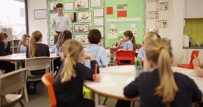 4K Elementary school teacher talking to his class of young children. Slow motion