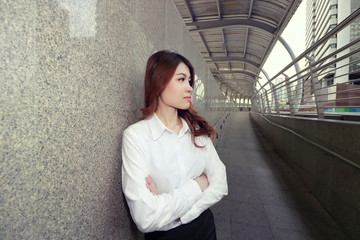 Wide angle shot of leadership young Asian business woman standing and looking confident against urban background.