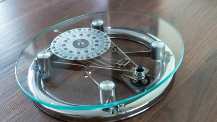 Modern glass and steel scale on a hardwood floor