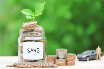 Stack of coins money in glass bottle and Miniature businessman standing with car on green background, Saving money for car, Finance and car loan, Investment and business concept.