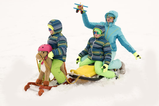 A happy mother with kids in sunglasses and a bright blue ski suit. Mother and children are happy together. A sports family on a snow-covered river with snow. Boys are very happy to play outdoors