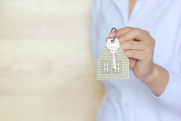Real estate agent concept, Woman hand holding key with a keychain in the shape of house