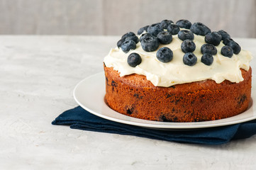 Sour cream blueberry cake served on a plate on a white stone background