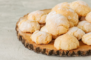 Homemade amaretti cookies on a wooden board on a white stone backdrop.