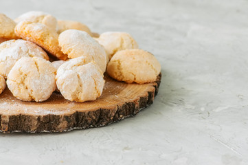 Homemade amaretti cookies on a wooden board on a white stone backdrop.