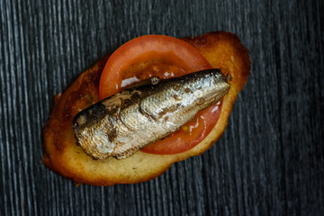 sandwich with sprats on a dark wooden background
