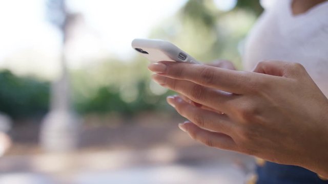 Beautiful female hands using a mobile cell phone outdoors