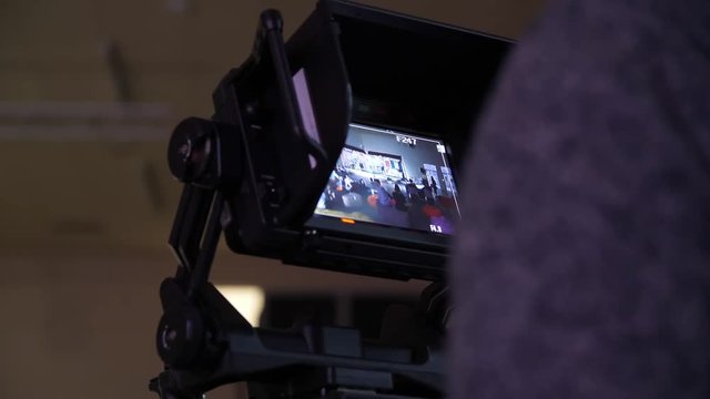 Behind the scene of tv movie video film shooting production crew team and camera lighting set in the big studio. Professional digital video camera in studio. Cameraman working with announcer in