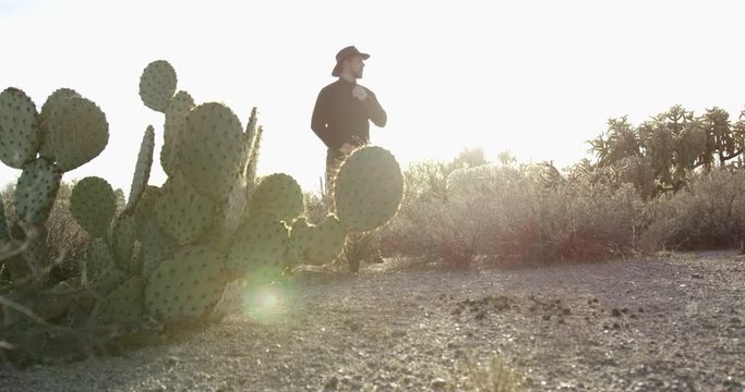 Cowboy adjusting shirt and colar while waiting in empty desert
