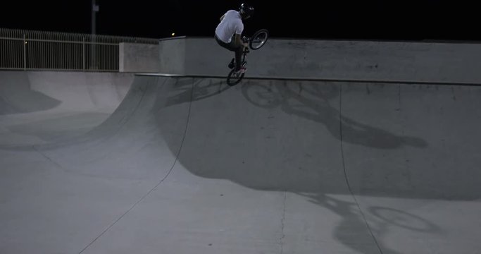 BMX rider rides skatepark at night