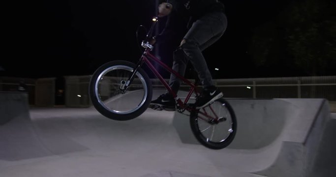 BMX rider jumps hip jump at night - close up