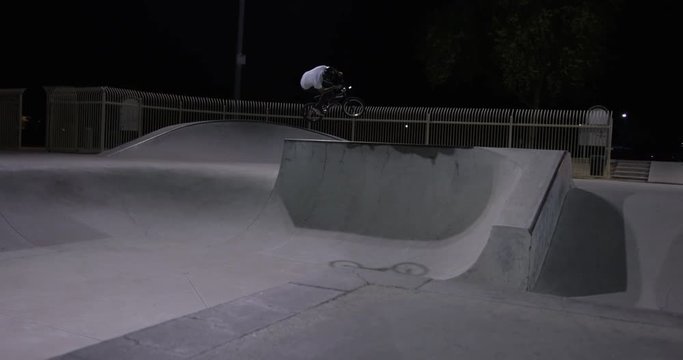 BMX rider jumps ramp at night