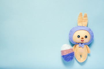 Easter rabbittoy with three color egg is on blue background.