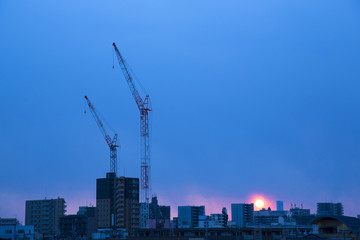 建設クレーンと都会の街並み
