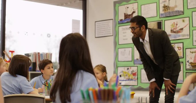 4K Caucasian primary school children listening attentively to Asian teacher in the classroom. Slow motion