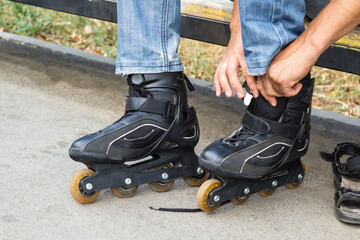 Closeup of man guy putting on roller skates outdoor