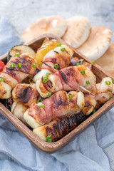 Grilled bacon wrapped haloumi with vegetables and pita