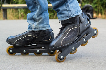 Young man in blue jeans riding roller skates in the city. Close up legs