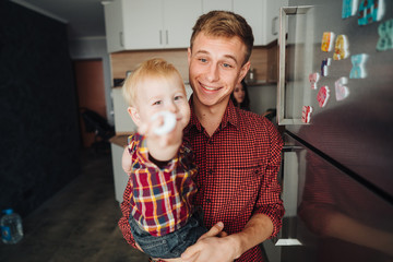 Dad and little son in the kitchen by the fridge