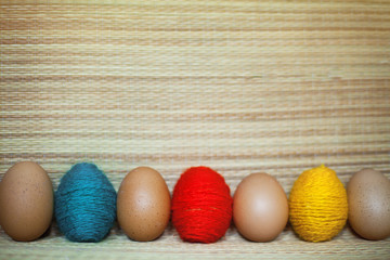 Red, yellow, green and brown eggs in the straw background.