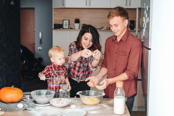 Dad, mom and little son cook a pie