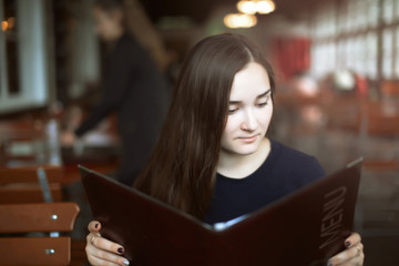 Young Woman Choosing from a Restaurant Menu - Young woman at a restaurant deciding what to order