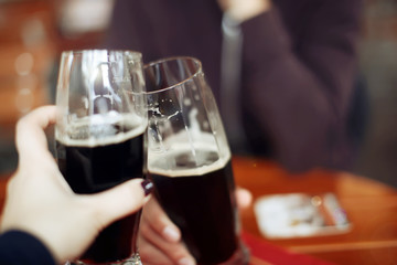 Two friends toasting with glasses of light beer at the pub. Beautiful background of the Oktoberfest. fine grain. Soft focus. Shallow DOF