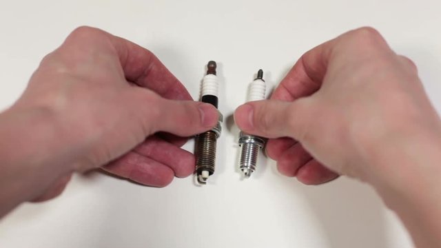 Compare of new and used spark plugs, human hand holding two sparkplugs