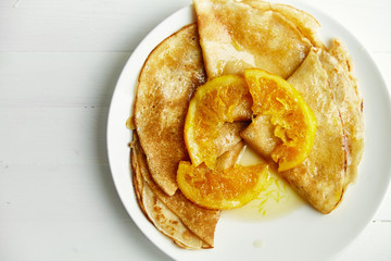 Overhead image of pancakes with orange confiture in white plate on wooden table