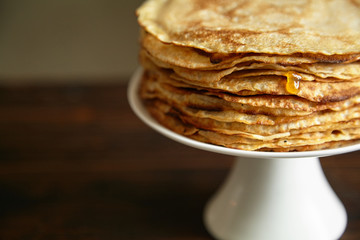 Crepes cake with orange jam and honey on white cake stand with text space. Pancake breakfast concept