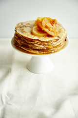 Crepes cake with orange jam and honey on white cake stand. Pancake breakfast concept