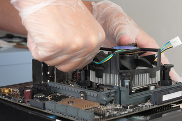 Close up of man hands installing CPU cooler fan on new, modern  motherboard