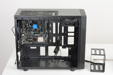 Building of PC, ATX motherboard inserted to black computer midi tower case.