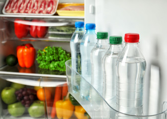 Bottles of cool water on refrigerator door shelf
