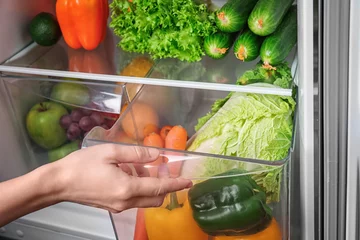 Gordijnen Woman opening drawer of refrigerator with vegetables © Africa Studio