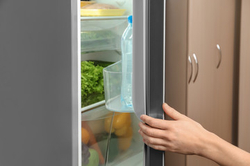 Young woman opening refrigerator, closeup