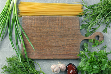 Fototapeta na wymiar Wooden board and products on grey background. Cooking master classes