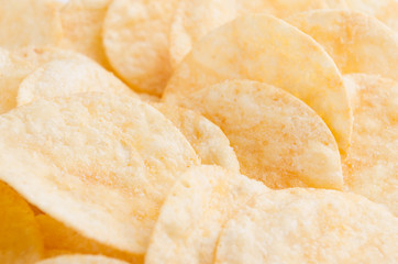 Crunchy potato chips with spices as background, closeup.