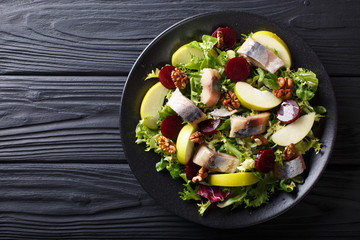 Smoked mackerel with apples, walnuts, beets and various lettuce close-up on a plate. horizontal top...